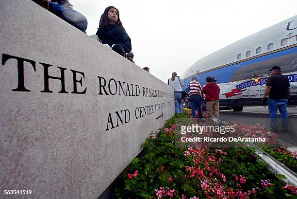 Caitlin Drake of Los Angeles, sitting on the sign at the gate to the Reagan library, watching Air Force One going by. This was "Operation Homeward...