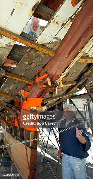 Doug Shumpert, lower right, watches as Randy Purdue, visible at top, drills a hole for a bolt which will help hold the rebuilt keel of the...