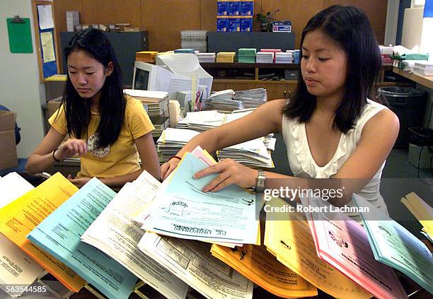 Students Bich Nguyen and Michelle Nguyen assemble registration packets as they work in the attendance office at Bolsa Grande High School.