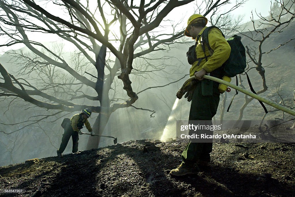 Chris Toole, of the U.S. Forest Service hosing down hot spots, right, and Kelly Kramer, of the U.S. 