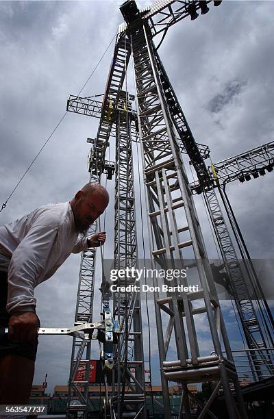 July 8, 2004. Anaheim. Stage supervisor Fred Holupka of Lakewood tightens a guy wire during construction of the stage in the infield at Anaheim...