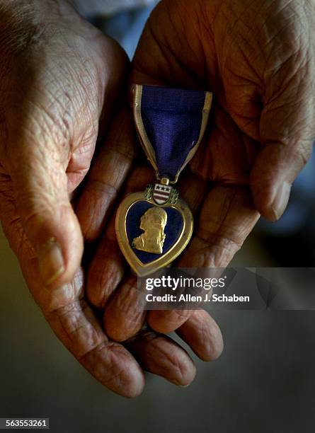 Veteran Bernard Stelzer, of Laguna Woods, shown holding one of two purple hearts he was awarded, was gunner of the Bim Bam Bola bomber that was shot...