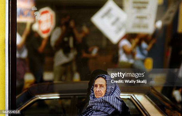 Woman stops along Whittier Blvd. To watch antiwar protestors march in East Los Angeles Sunday.