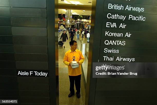 James Oh waits for travellers while campaigning for Korean presidential candidate Roh MuHyun at the Bradley terminal at LAX Friday Dec. 13. Though...