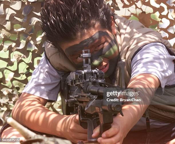 With his faces painted camouflage, Wilfredo Majano plays with an unloaded M60 machine gun on display at Seabee Days at Naval Base Ventura County,...