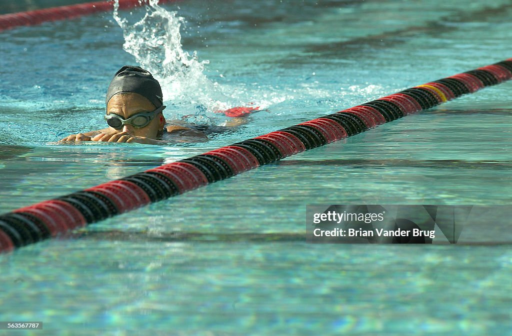 A lap swimmer glides through the water with a paddle board at the Rose Bowl Aquatic Center in Pasade