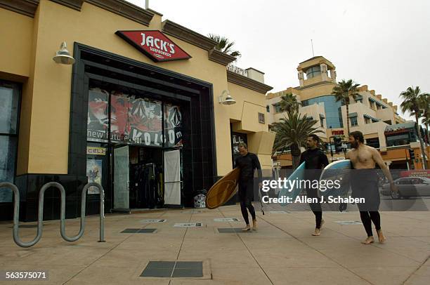 Surfers Mike Driskill of Huntington Beach, left, Mike Schober of La Mirada, center, and Leigh Gotsman of Huntington Beach, walk along Jack's Surf...