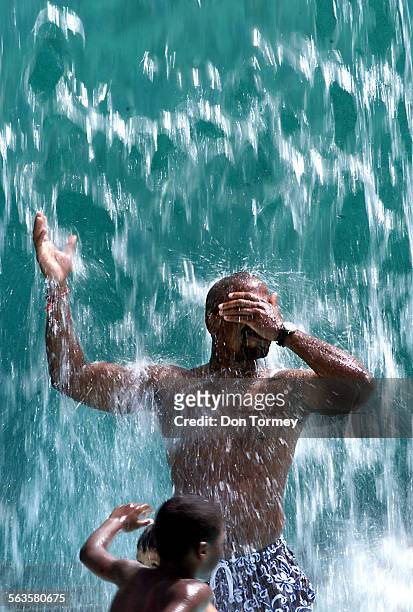 Adults and children alike enjoy cooling off in the waterfall at Typhoon Lagoon children's play area of the Wild Rivers Waterpark in Irvine today as...