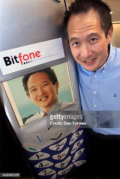 Gene Wang, Chairman and CEO of Bitfone Corp., next to a lifesize cellphone electronic message board that displays his photo as well as displaying the...