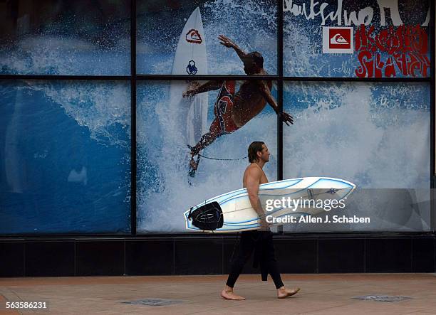 Surfer John Davies of Huntington Beach walks along Jack's Surf Shop's Surfing Walk of Fame after a surf session Friday, May 23, 2003 in Huntington...
