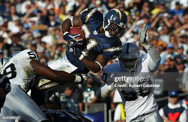 San Diego Charger running back LaDainian Tomlinson leaps past Oakland Raiders linebacker Eric Barton to score a second quarter touchdown, Sunday...