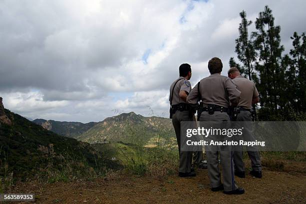 Officers look over cliff after a charred body was found in a vehicle that crashed and caught fire in Agoura Hills. The body was discovered in a...