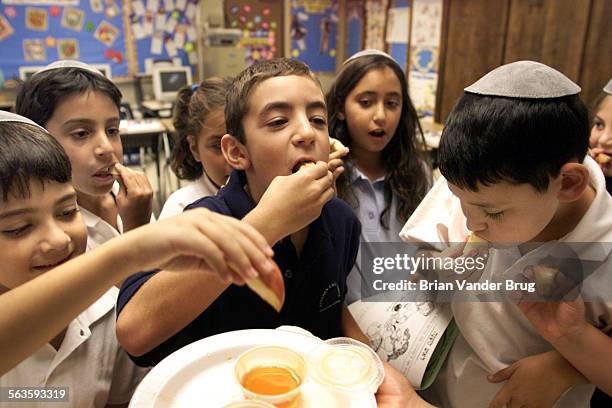 Stephen S. Wide Temple Elementary School third graders dip apples in honey during a lesson on Rosh Hashana in class Thursday morning September 5 2002...