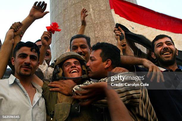 Lance Corp. Shawn Hicks, of Arizona, of the Marines 3rd Battallion from Camp Pendleton, CA., gets a kiss from an Iraqi man as they celebrate the...