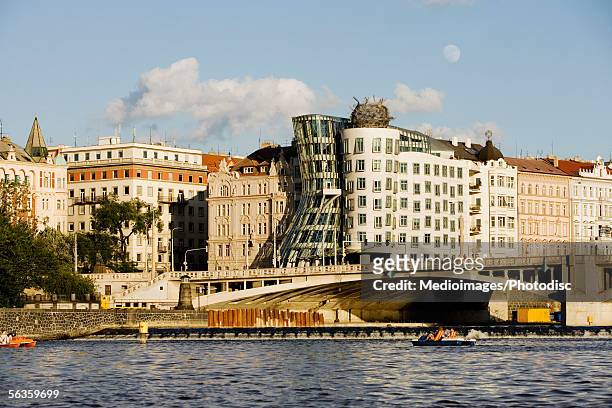 buildings on a waterfront, new town, dancing house, jiraskuv bridge, prague, czech republic - vltava river stockfoto's en -beelden