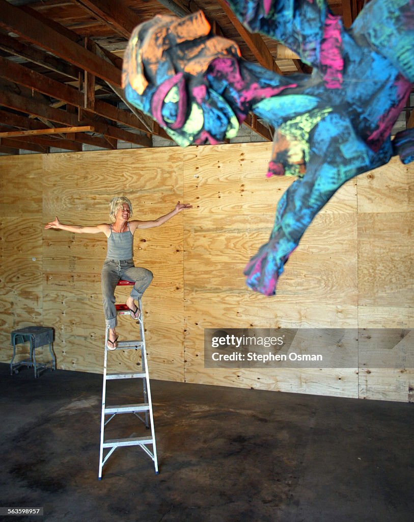 Ventura artist M.B. Hanrahan sits atop a ladder in her new studio at the shuttered Bell Mattress Fac