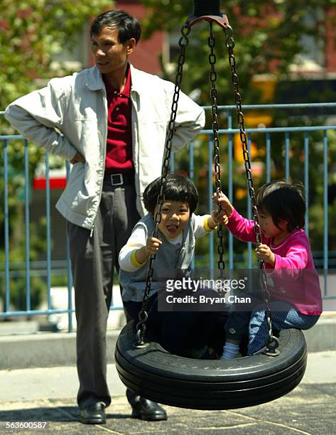 Helen and her sister Elley play on a swing as their father Jin Quan Yu stands by in Chinatown's Portsmouth Square. San Franciscos Chinese communities...
