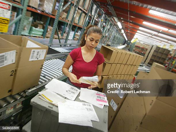 Shipping clerk Alma Lopez checks an order before selecting a box for shipping at the Ingram Micro warehouse in Mira Loma.