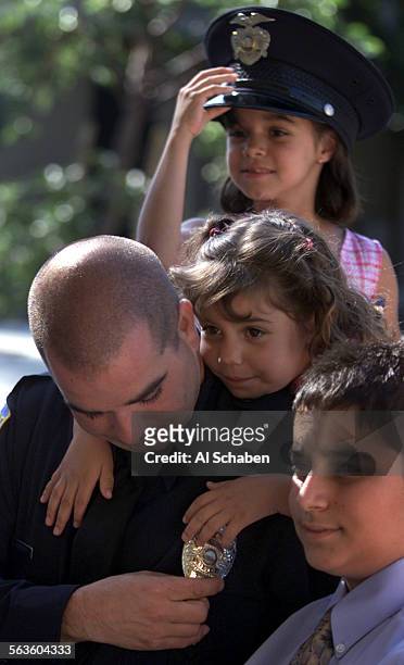 Anthony Saporito, looks at his new sheild while being swamped by his children, Gabriella Saporito back, Giovanna Saporito center hugging her dad, and...