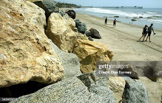 Beach strollers walk past huge boulders that line the sand north of the pier near Mariposa and Escalones Streets where pedestrians access the beach....