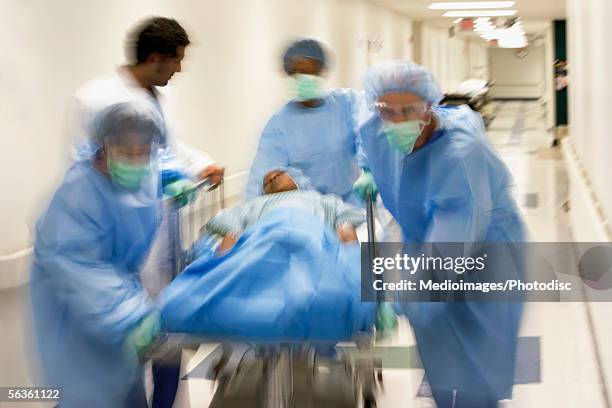 doctor and assistants with patient on hospital gurney in hospital corridor - hospital gurney stock pictures, royalty-free photos & images