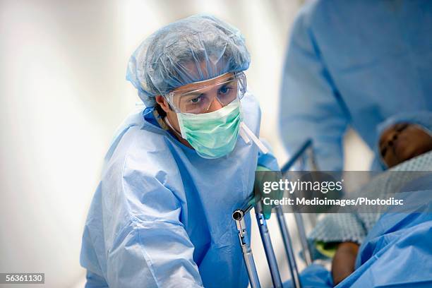 surgical team rolling patient down corridor to surgery - stretcher photos et images de collection