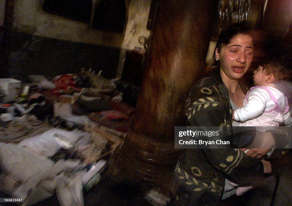 Sandy Shalin, 18, holding daughter Lourdes, weeps as she views the mess left behind by the Palestini