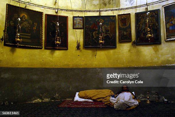 Fg.0510.church.2 Religious paintings hang above a lone Christian resting inside the Church of the Nativity in Bethlehem in the last week of the siege...