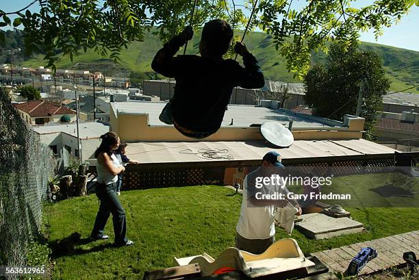 Roxanna Villa holds her son, Dustin Serrano, age 1, as her daughter Miranda Villa, age 6, sits on the steps in the backyard of the home she shares...