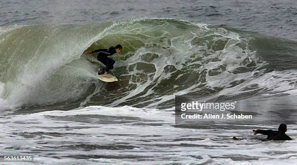 Surfer catches a tube ride as surf was breaking six to nine feet on the faces at 48th Street jettie in Newport Beach Friday, June 4, 2004.