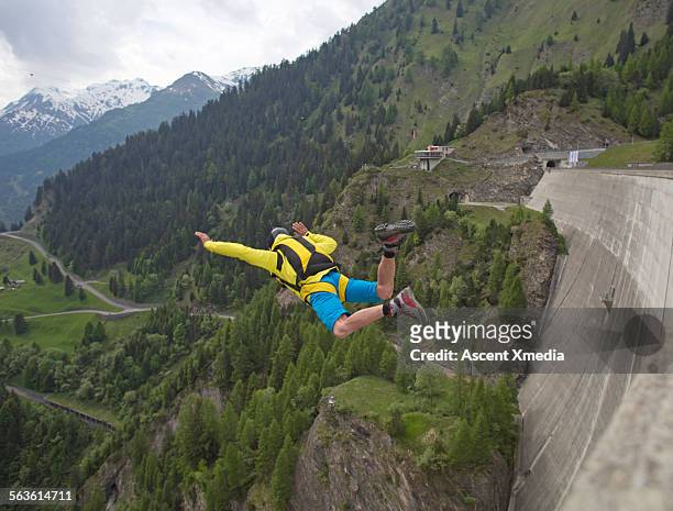 base jumper in free fall down face of concrete dam - base jumping stock pictures, royalty-free photos & images