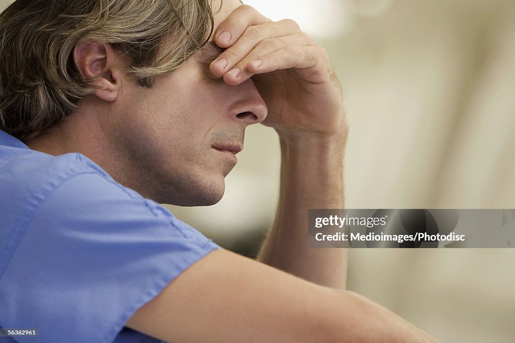 Close-up of a male doctor with his hand on his head