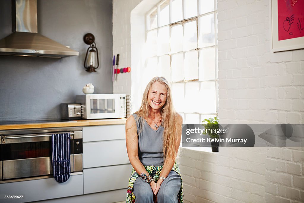 A portrait of older woman sitting in a kitchen
