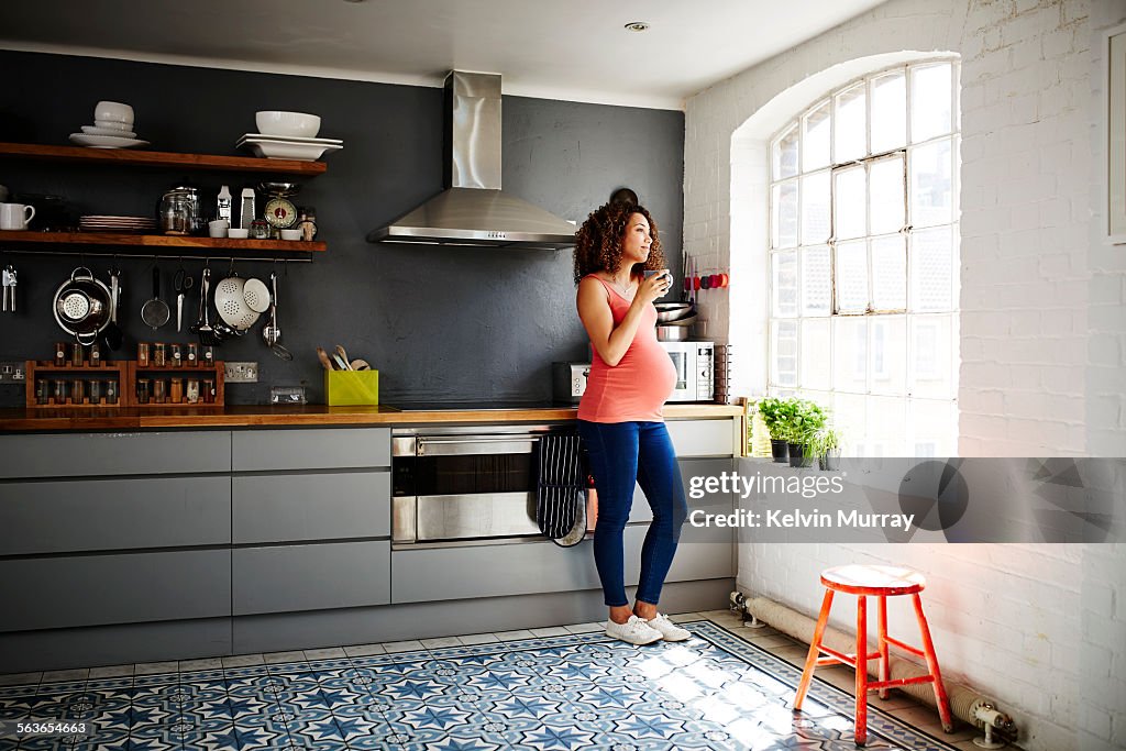 A pregnant lady looks out of her kitchen window