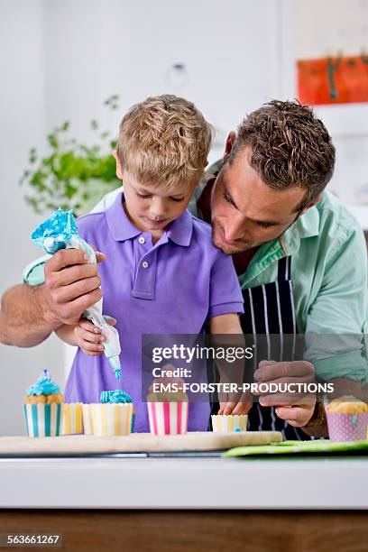 single father is decorating cupcake with his son - cupcake fotografías e imágenes de stock