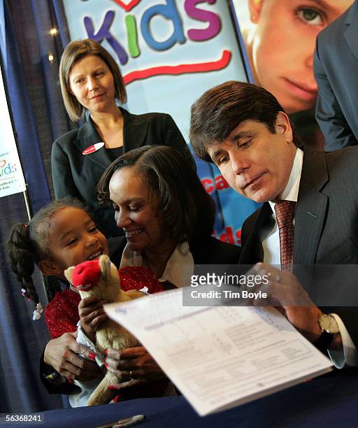 Illinois Governor Rod Blagojevich looks at a finished "All Kids" insurance application form filled out by Chicago resident Evette Neal for her...