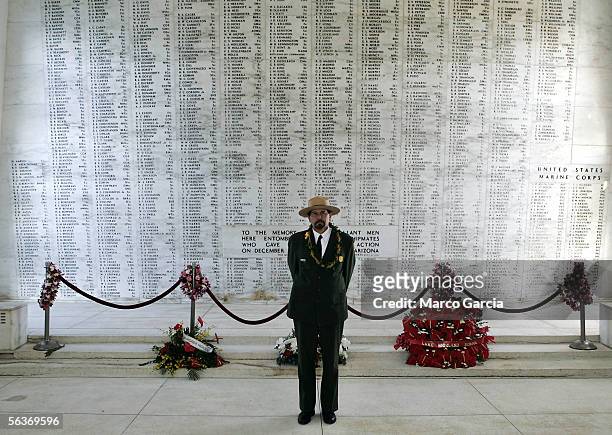 National Parks Service Ranger Daniel Martinez stands in front of the memorial wall on the USS Arizona Memorial during the ceremony honoring the 64th...