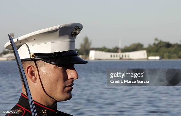 With the USS Arizona Memorial in the background, a U.S. Marine stands at attention during the ceremony honoring the 64th anniversary of the surprise...