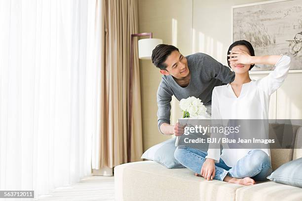 young man surprising wife with flowers - man giving flowers foto e immagini stock