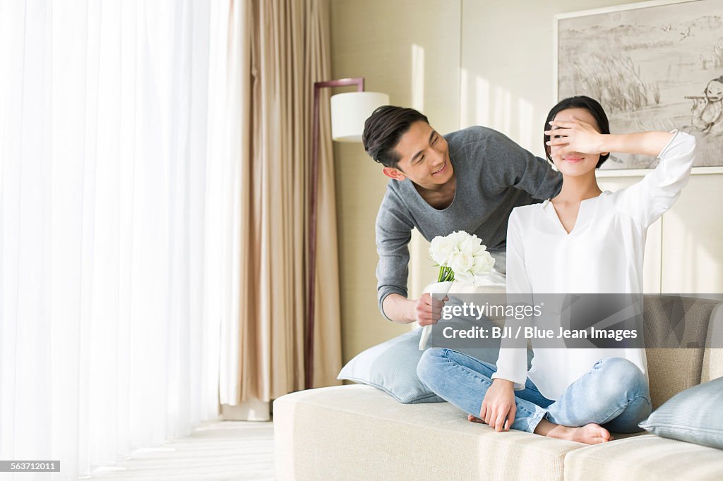 Young man surprising wife with flowers