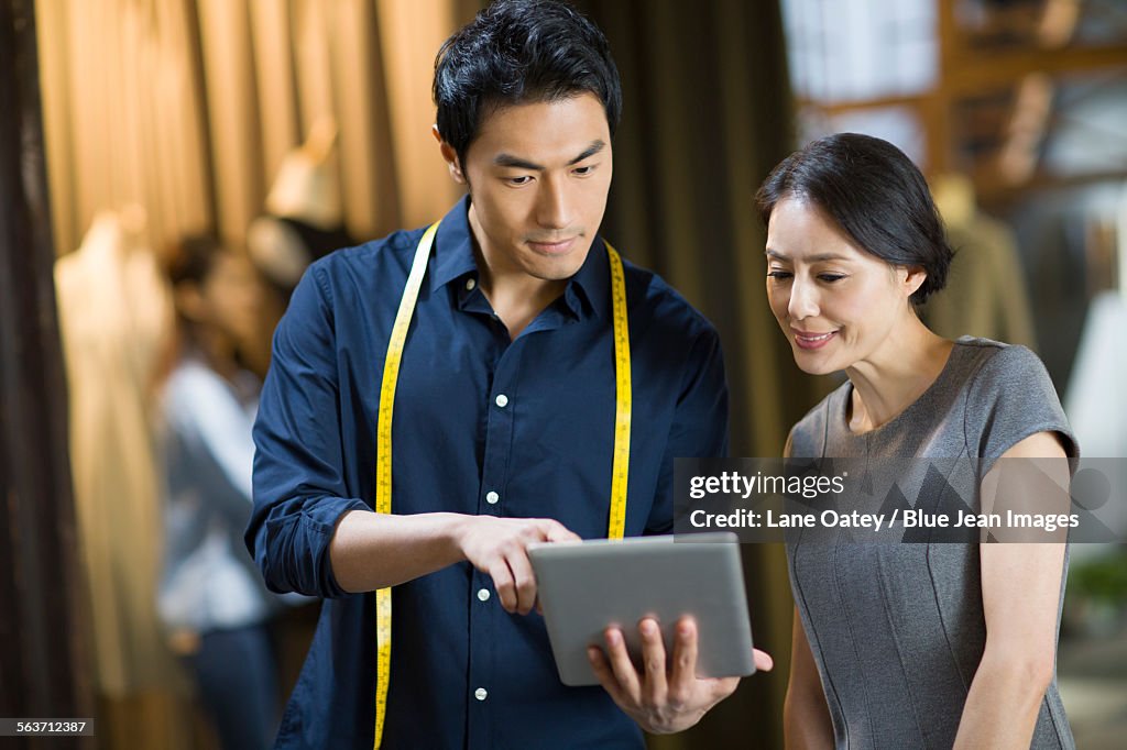 Fashion designers and customer looking at digital tablet