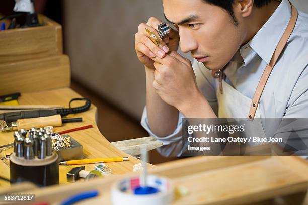 male jeweler examining a diamond with loupe - examining diamond stock pictures, royalty-free photos & images