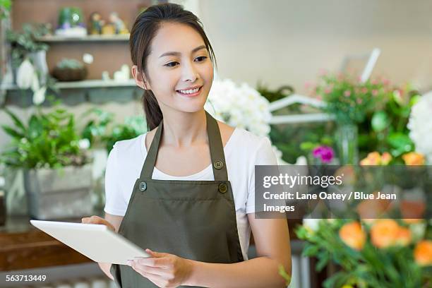 female florist using digital tablet in shop - asia lady selling flower fotografías e imágenes de stock