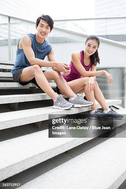 young couple resting on the stairs after exercise - balustrade stock pictures, royalty-free photos & images