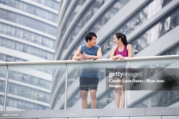 young couple taking a break from exercise to talk - balustrade stock pictures, royalty-free photos & images