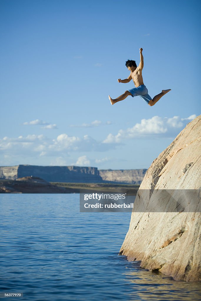 Low angle view of a young man jumping into a lake