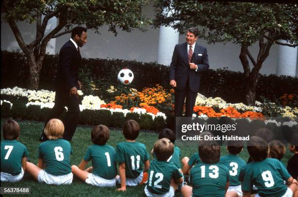 Brazilian soccer star Pele , dressed in a suit, demonstrates ball control to a children's soccer team seated in the Rose Garden at the White House as...