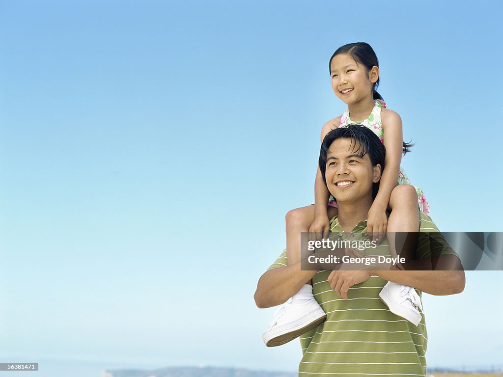 Close-up of a father carrying his daughter on his shoulders