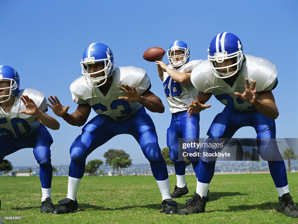 Four football players playing on a football field