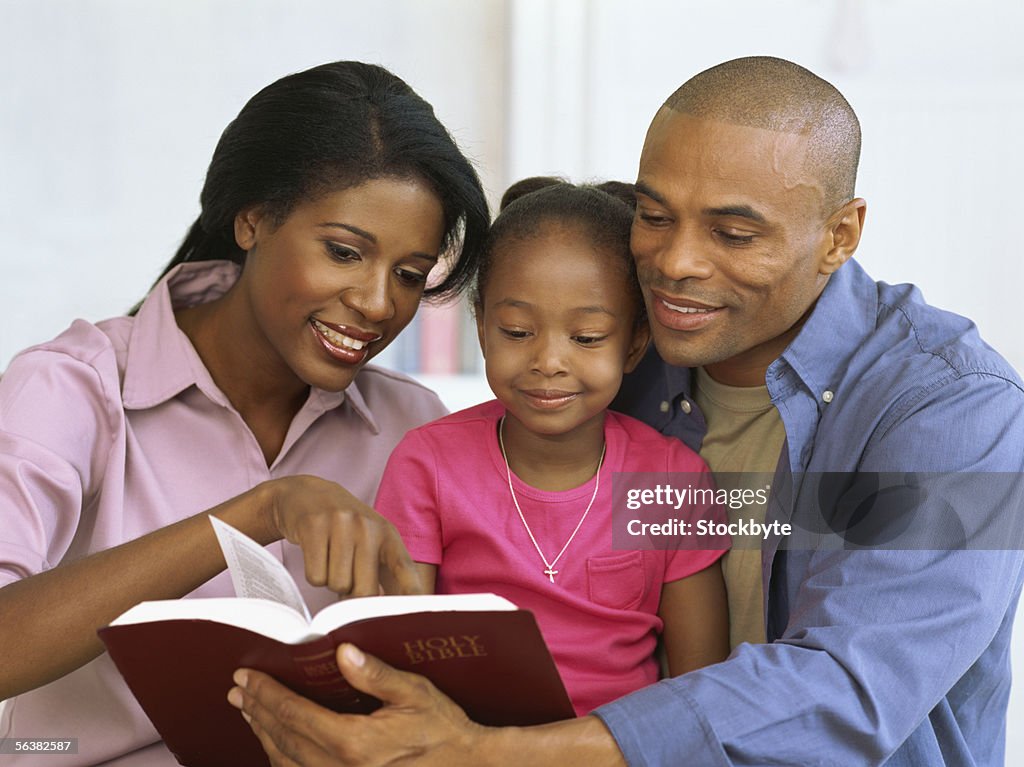 Parents and their daughter reading the bible